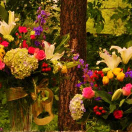 Two colorful floral arrangements with lilies, roses, and hydrangeas outdoors