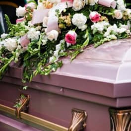 Pink and white floral casket spray on a mauve casket