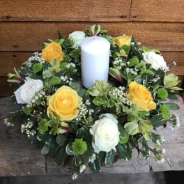 Round floral wreath with a white pillar candle in the center