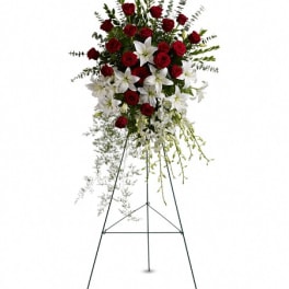 Standing floral spray with red roses and white lilies on an easel