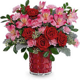 Bouquet of red roses and pink alstroemeria in a red glass vase