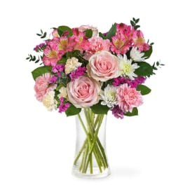 Pink roses and mixed flowers in a clear glass vase