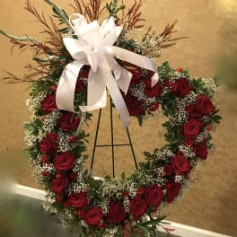 Large red rose wreath with white ribbon on a stand