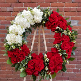 Heart-shaped wreath of red and white roses on a wooden easel