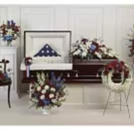 Multiple patriotic floral funeral arrangements with red, white, and blue flowers
