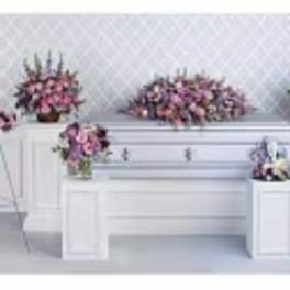 Pink floral funeral casket spray with matching standing arrangements