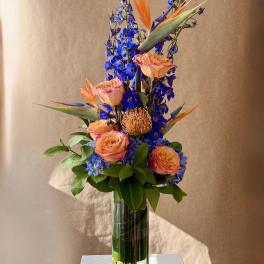 Tall bouquet of orange and pink flowers in a clear glass vase