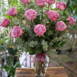 Pink roses arranged in a clear glass vase with greenery