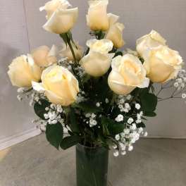 Cream roses arranged in a clear glass vase with small white filler flowers