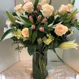 Bouquet of peach roses and white lilies in a glass vase
