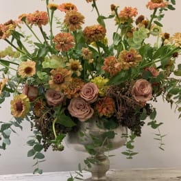 Mixed peach and pink flowers in a silver pedestal vase
