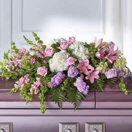 Pink and white floral casket spray with lilies, roses, and hydrangeas