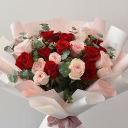 Bouquet of red and pale pink roses wrapped in white paper