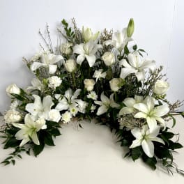 White lilies and roses arranged in a low, wide floral display