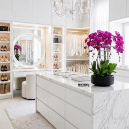 Potted purple orchids in a black planter on a marble counter