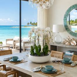 White orchids in a low bowl centerpiece on a dining table