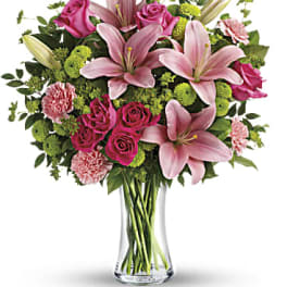 Pink lilies, roses, and carnations in a clear glass vase