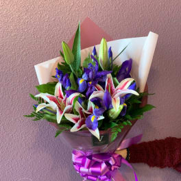 Bouquet of purple irises and pink-white lilies wrapped in paper