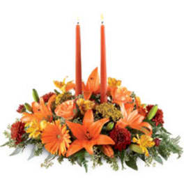 Orange floral centerpiece with two tall candles
