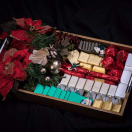 Tray of assorted wrapped chocolates with red poinsettias and holiday decorations