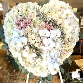 Heart-shaped white floral standing arrangement with pink roses and orchids