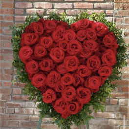 Heart-shaped arrangement of red roses with green foliage on an easel