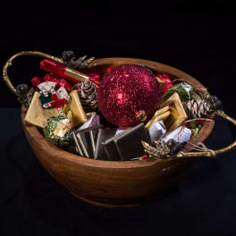 Wooden bowl filled with wrapped chocolates and a red glitter ornament