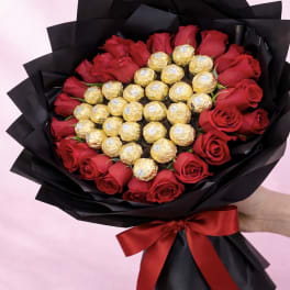 Bouquet of red roses with gold-wrapped chocolates in black paper