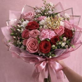 Pink and red rose bouquet wrapped in pink paper with a satin ribbon