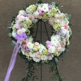 Pastel floral wreath on a stand with a lavender ribbon