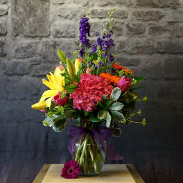 Colorful bouquet of lilies, hydrangea, and purple flowers in a glass vase