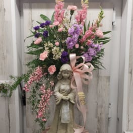 Tall floral arrangement with pink and purple blooms on a statue base