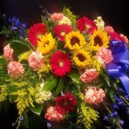Colorful bouquet with sunflowers, red gerbera daisies, and pink carnations tied with a blue ribbon