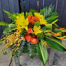 Bright tropical bouquet with yellow and orange flowers and lush greenery