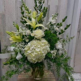 White floral arrangement with lilies, roses, and hydrangea in a glass vase