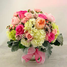 Pink and peach rose bouquet with pale hydrangeas in a glass vase