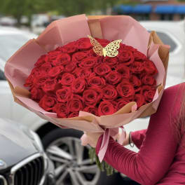 Large bouquet of red roses wrapped in pink paper with a butterfly topper