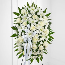 White floral standing spray with roses and lilies on an easel