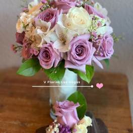 Lavender and white rose bouquet in a glass vase with a ribboned rose corsage below