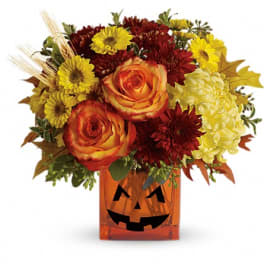 Autumn bouquet in a jack-o'-lantern vase with orange roses and yellow daisies