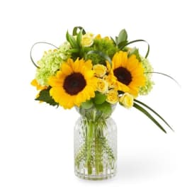 Sunflower and yellow rose arrangement in a clear glass vase