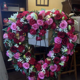 Heart-shaped floral wreath with pink and red roses on a stand