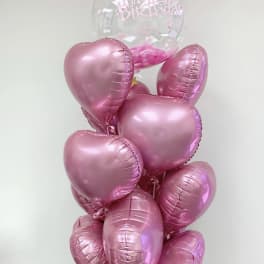 Cluster of pink heart balloons with a clear Happy Birthday balloon on top
