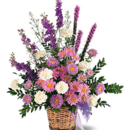 Pink and white mixed flowers in a wicker basket with a ribbon