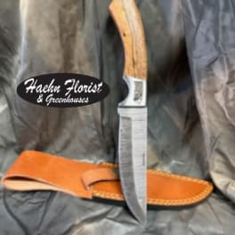 Hunting knife with a leather sheath on dark fabric