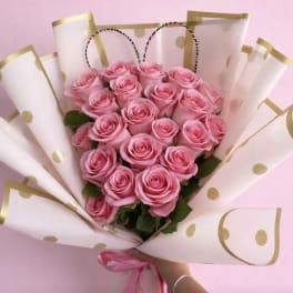 Pink rose bouquet wrapped in white paper with gold dots