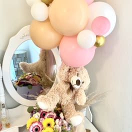 Teddy bear with pastel balloons and a flower box arrangement