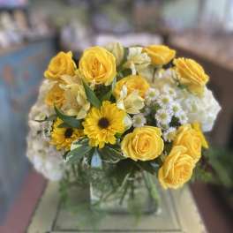 Yellow roses and daisies arranged in a glass vase