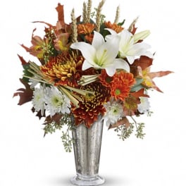 Tall autumn arrangement with white lilies and orange and white chrysanthemums in a silver vase