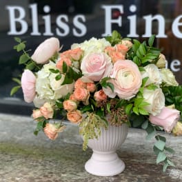 Blush and cream floral arrangement in a white pedestal vase